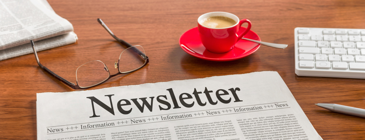 An image of a desk with a laptop on it and paper with the words 'newsletter'
