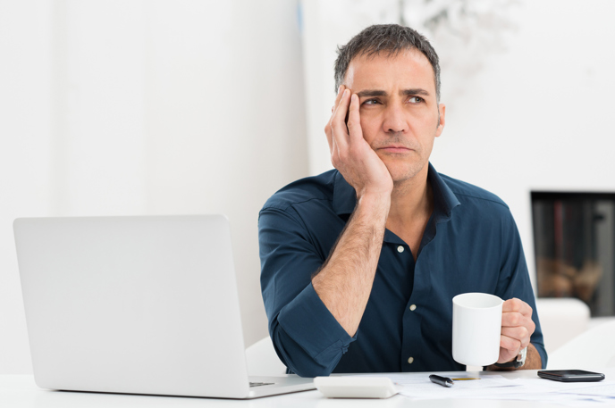 MAN LOOKING PENSIVE ON LAPTOP
